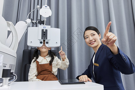 眼镜店验光师正在给小女孩检测视力背景图片