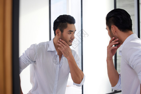 男浴室成熟男人站在镜子前整理胡子背景