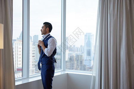 窗前打领带的成熟男性高清图片