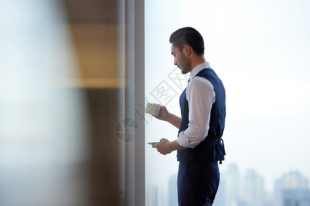 成熟商务男性站在窗前喝咖啡图片