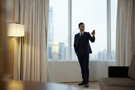 商务男性使用手机操控智能家居设备图片