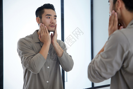 成熟男士对着镜子护理皮肤背景图片