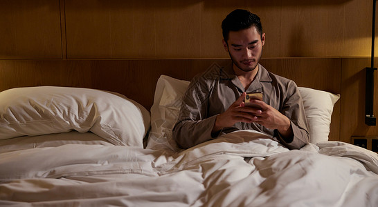 深夜男子躺在床上玩手机图片