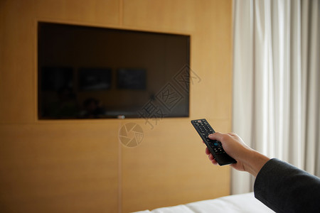 便捷酒店使用遥控器打开电视手部特写背景