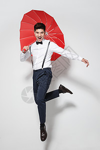 享乐青年男人拿着红雨伞跳跃图片