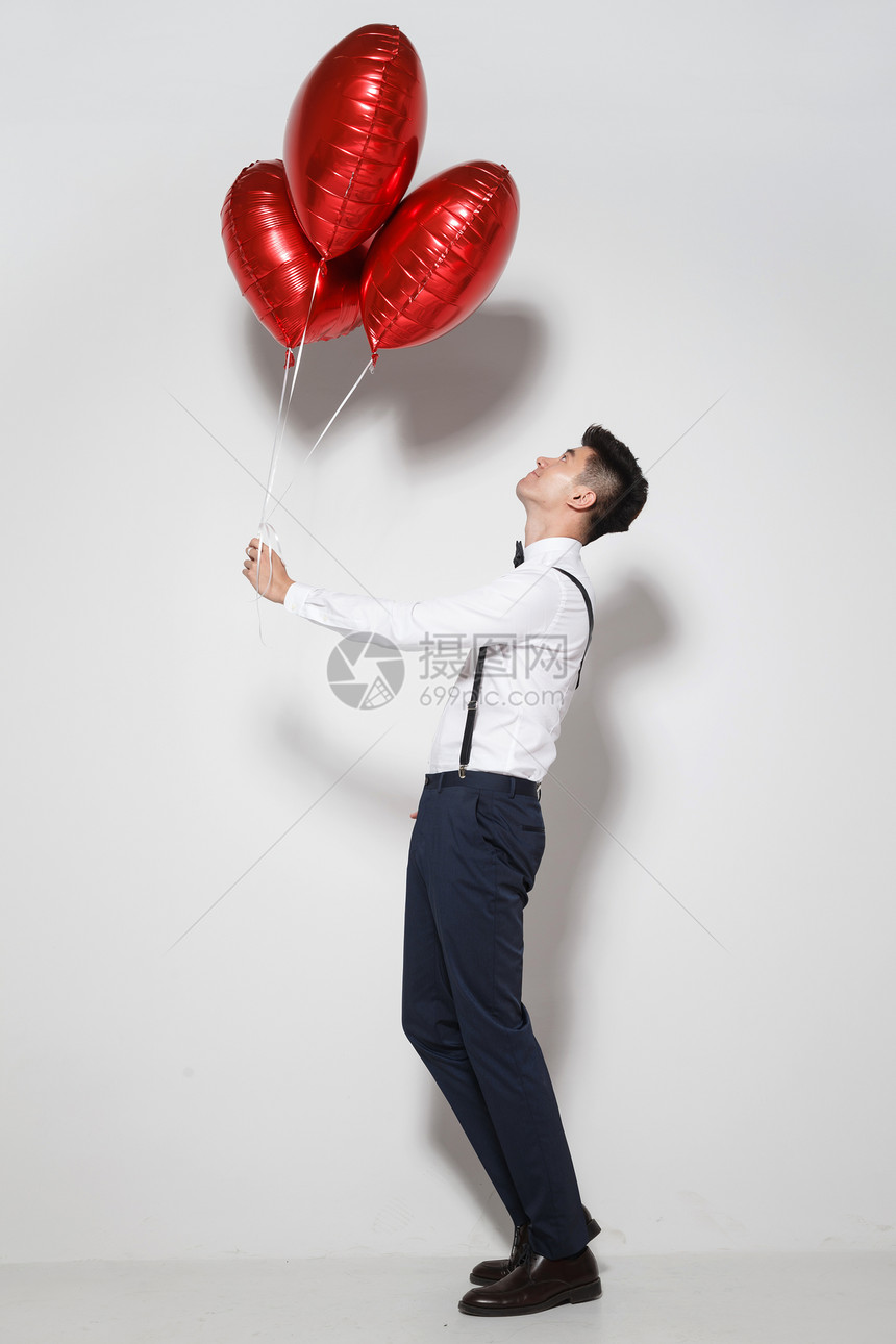 影棚拍摄订婚愉悦青年男人拿着心形气球图片
