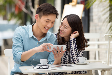 青年情侣坐在咖啡馆看手机高清图片