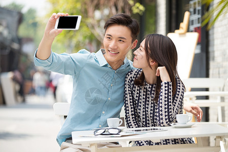 青年情侣坐在咖啡馆里用手机自拍图片