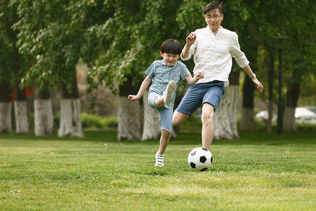 快乐父子在草地上踢足球高清图片