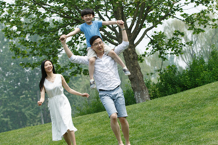 享乐户外背着一家三口在草地上玩耍图片