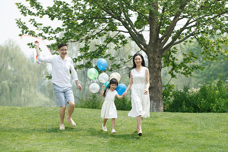 家庭生活双亲家庭休闲装一家三口在草地上玩耍图片