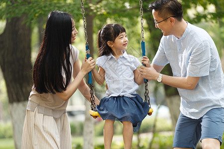 青年人独生子家庭休闲快乐的一家三口荡秋千图片