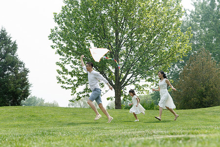 草地上放风筝愉悦水平构图天真一家三口在草地上玩耍背景