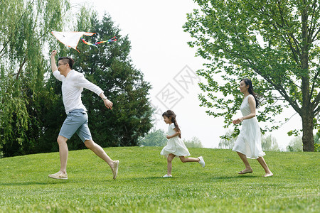 愉悦青年女人绿色一家三口在草地上玩耍图片