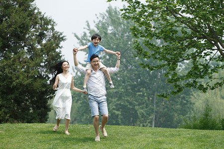 欢乐健康生活方式休闲装一家三口在草地上玩耍图片