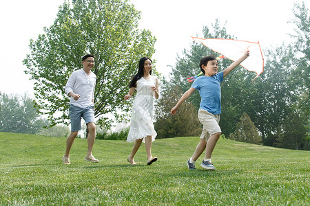非都市风光白昼青年女人一家三口在草地上放风筝图片