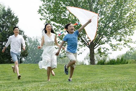 幸福欢乐一家三口在草地上放风筝图片