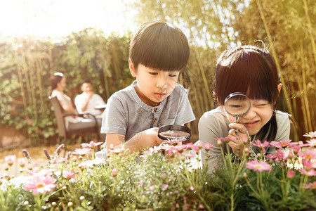 放大镜的人两个儿童在庭院里玩耍背景