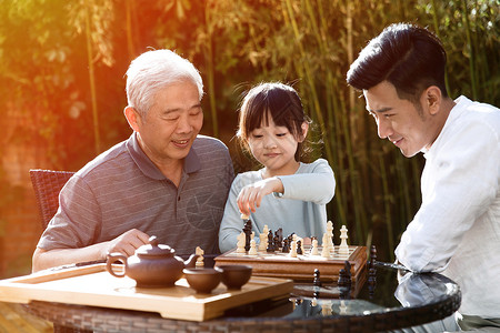 幸福永远快乐祖孙三代在庭院里下棋背景