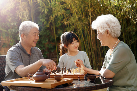 棋盘游戏象棋妻子老年夫妇和孙女在院子里下棋高清图片