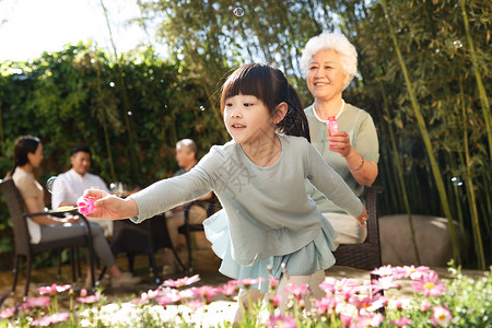 花园里吹泡泡夏天幸福家庭在庭院里玩耍背景