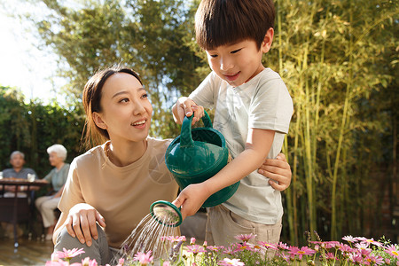 小朋友浇水夏天幸福家庭在庭院里浇花背景