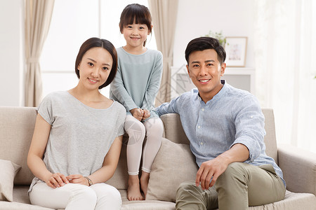 核心家庭父母双亲家庭幸福的一家三口坐在客厅里图片