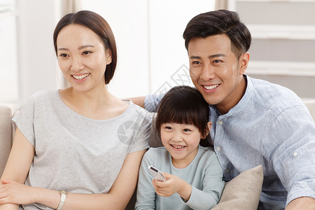 一家看电视艺术文化和娱乐关爱双亲家庭幸福的一家三口在客厅看电视背景