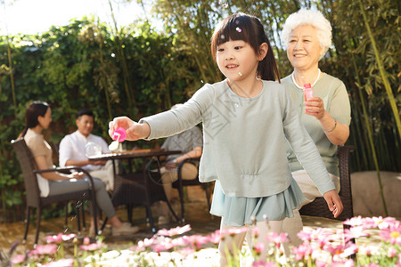 花园里吹泡泡幸福的家庭在庭院里避暑背景