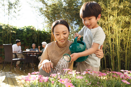 小朋友浇水幸福的家庭在庭院里避暑背景