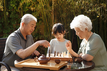 联系三个人老年夫妇和孙女在院子里下棋高清图片