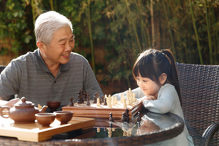 欢乐老年人象棋祖父和孙女在庭院里下棋高清图片