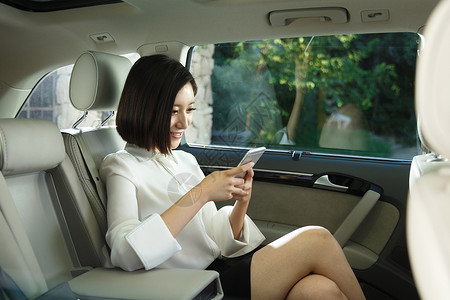 汽车业汽车内部青年女人坐在汽车里看手机背景