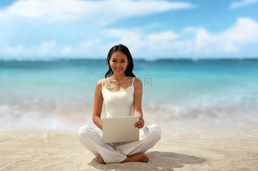 在海边使用笔记本电脑的女青年图片