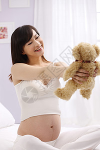 关爱女人轻松孕妇拿着玩具熊图片