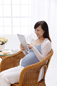 摄影杂志摄影微笑东亚孕妇看平板电脑背景