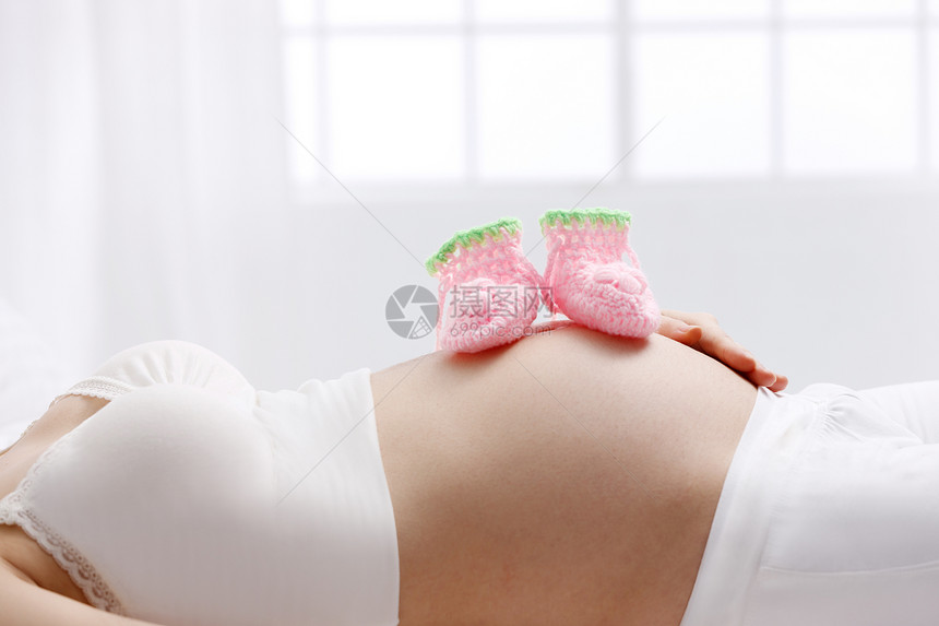 轻松纺织品青年女人婴儿袜子放在孕妇的肚子上图片