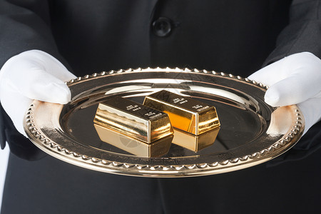 黄金产业服务员拿着托盘里的金条背景