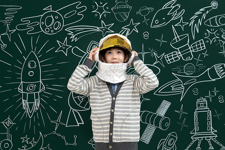 教室戴着航天员头盔的小男孩站在黑板前高清图片