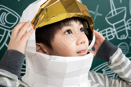 摘星星孩子星学生天文学戴着航天员头盔的小男孩站在黑板前背景