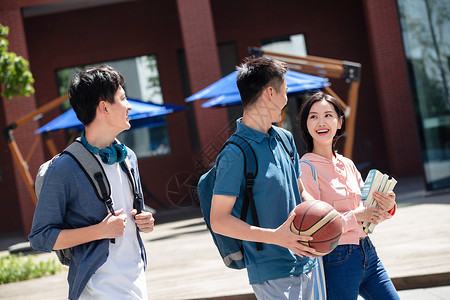 抱着篮球的男孩下课后的大学生步行在校园里背景