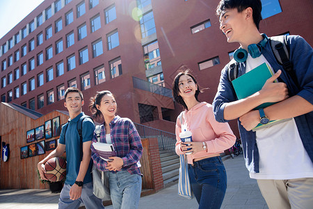 阳光下青年大学生情侣在校园里边走边聊图片