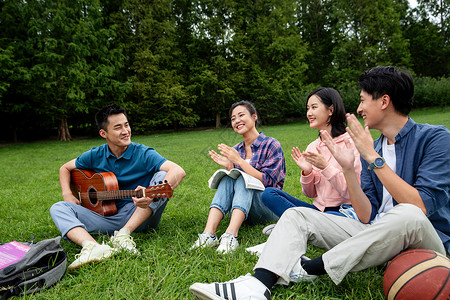 积极快乐的大学生在草地上弹吉他唱歌图片