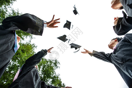 新毕业生穿着学士服的大学生扔学士帽背景