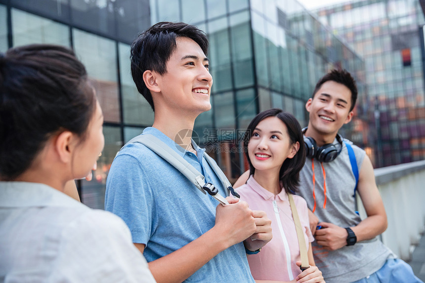 户外四个大学生一起靠在护栏上闲聊图片