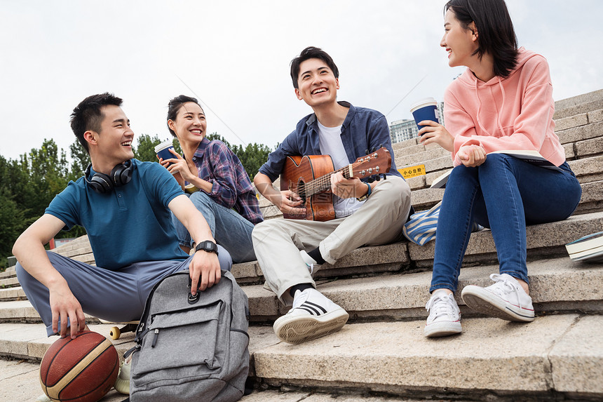 高兴的青年伴侣友谊年轻的大学生坐在台阶上弹吉他图片