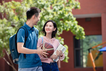 两个篮球大学生情侣在校园里行走背景