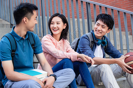 楼梯护栏青年男人关爱高兴的大学生坐在户外的楼梯上闲聊背景