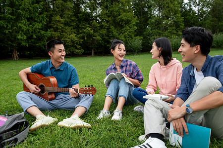 骄傲女朋友成年人快乐的大学生在草地上弹吉他唱歌高清图片