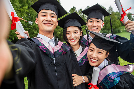 表现积极的四个身穿学士服的大学生一起自拍图片